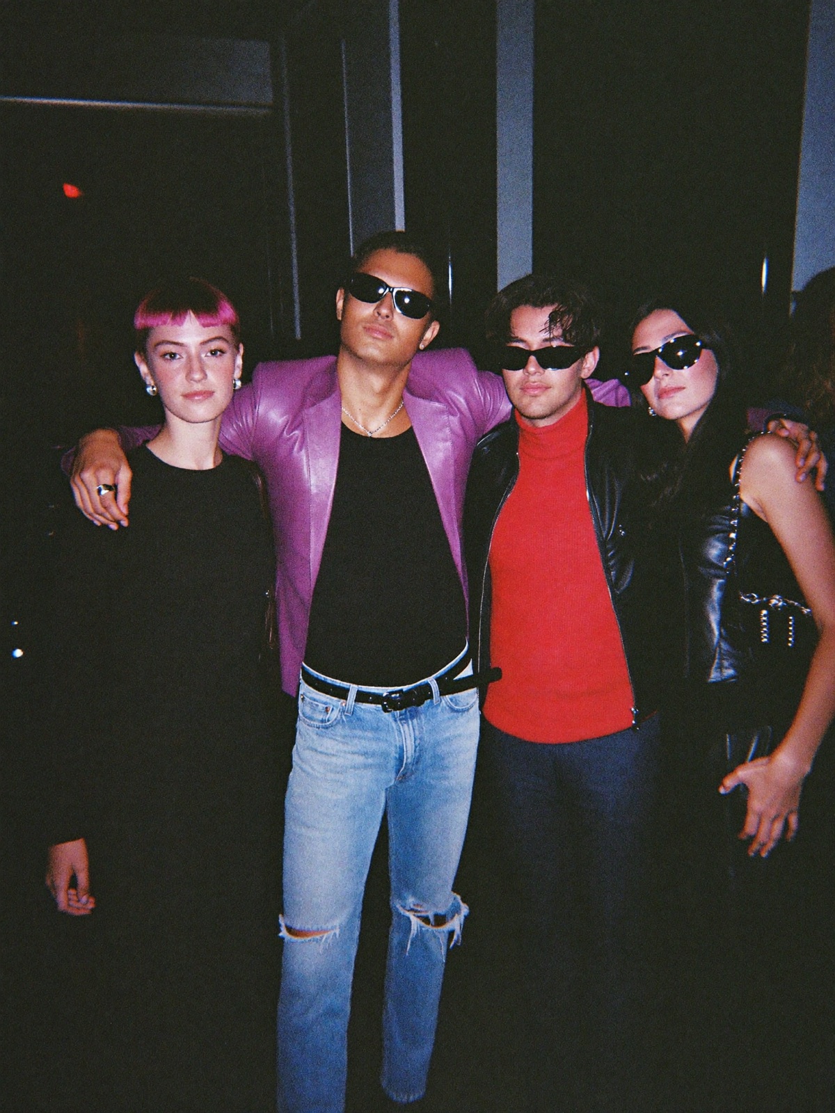 Four stylish friends posing in a corridor