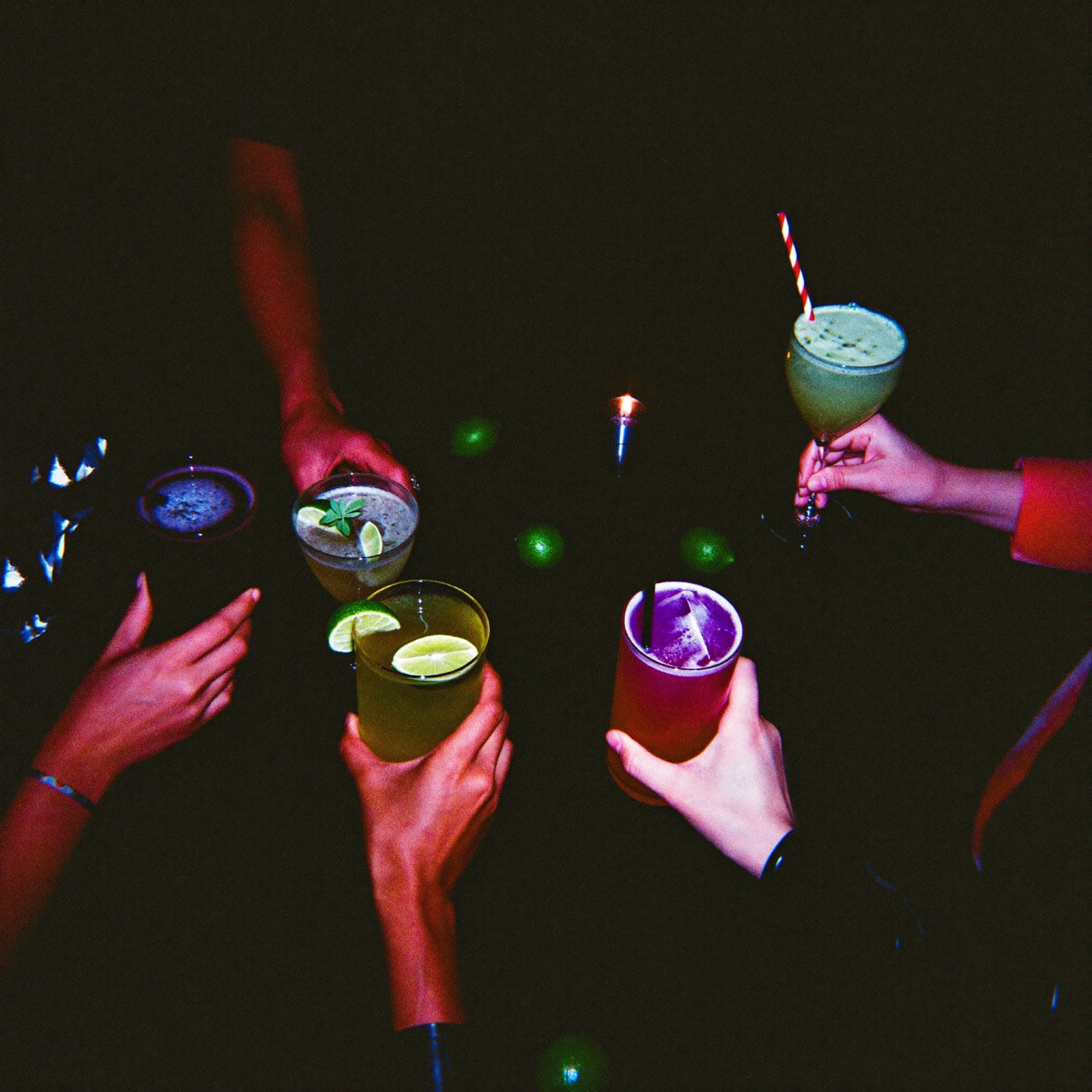 Six hands holding cocktails over a table